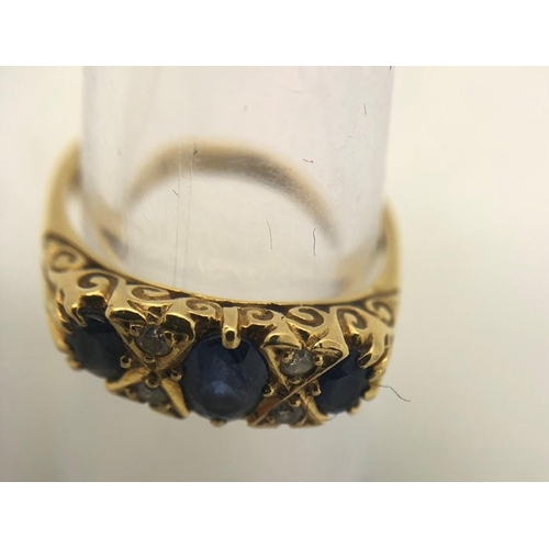 569 - A 3 stone sapphire and diamond ring in 18ct yellow gold, size N. 3.1gms.