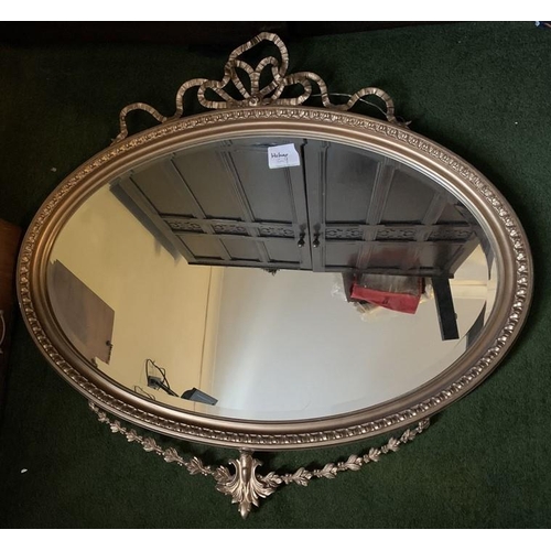 1244 - Oval gilt framed wall mirror. 39 x 75cms. Decorative bow to top and swag to base.