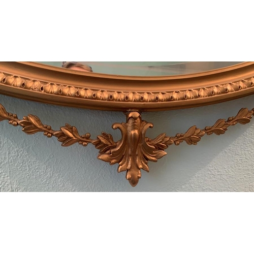 1244 - Oval gilt framed wall mirror. 39 x 75cms. Decorative bow to top and swag to base.