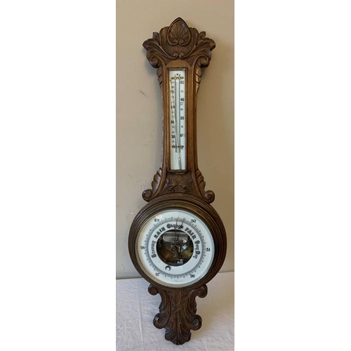 1287 - An oak cased aneroid barometer with carved body, 87cms h.