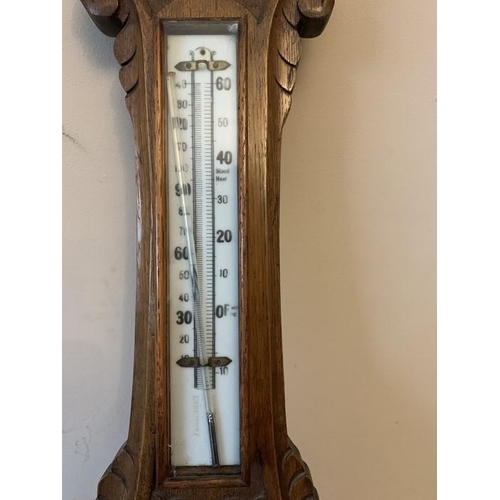 1287 - An oak cased aneroid barometer with carved body, 87cms h.