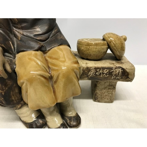 265 - Chinese ironstone pottery figurine, Man combing ladies hair sat on a bench, signed to bench front, s... 