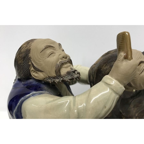 265 - Chinese ironstone pottery figurine, Man combing ladies hair sat on a bench, signed to bench front, s... 