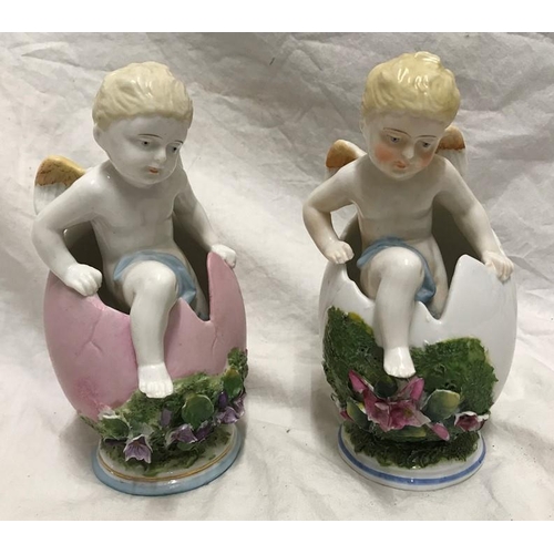 323 - Continental porcelain pair of figurines, winged cherubs in eggs with floral decoration, 18cms h.