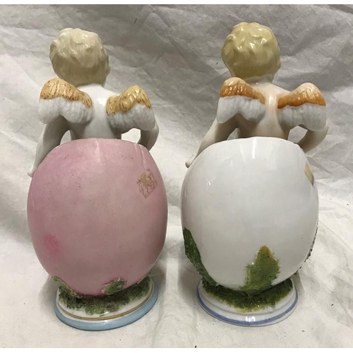 323 - Continental porcelain pair of figurines, winged cherubs in eggs with floral decoration, 18cms h.