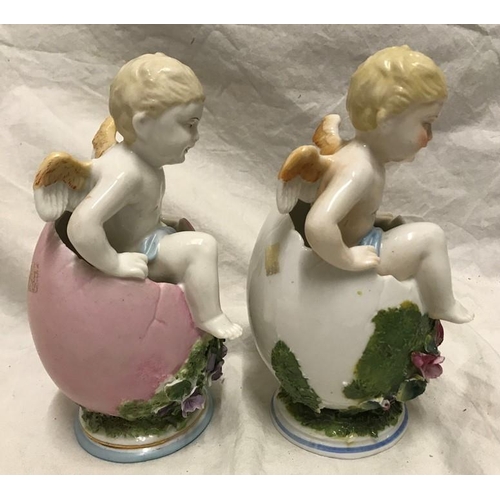 323 - Continental porcelain pair of figurines, winged cherubs in eggs with floral decoration, 18cms h.