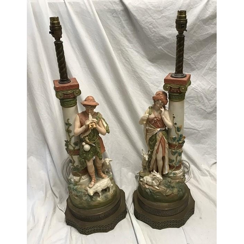 325 - Pair of continental pottery figurine table lamps, Male and Female with goats and lambs beside a colu... 