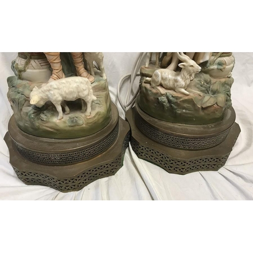 325 - Pair of continental pottery figurine table lamps, Male and Female with goats and lambs beside a colu... 