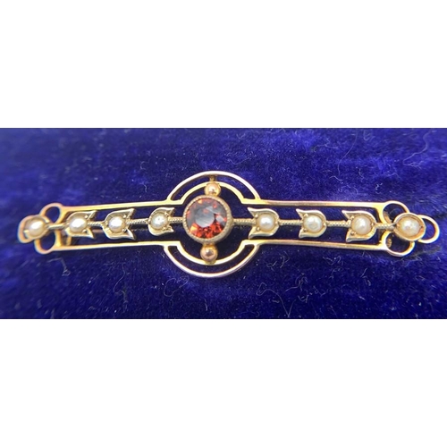 702 - A 9ct gold bar brooch set with eight seed pearls and a central red stone in original silk lined box.... 