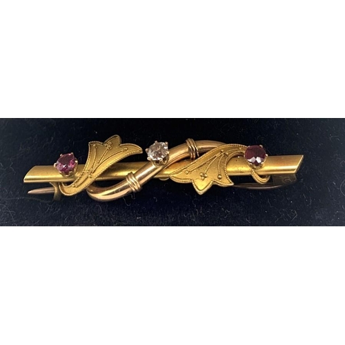 703 - A 15ct gold bar brooch set with central diamond flanked by red stones to each side in original fitte... 