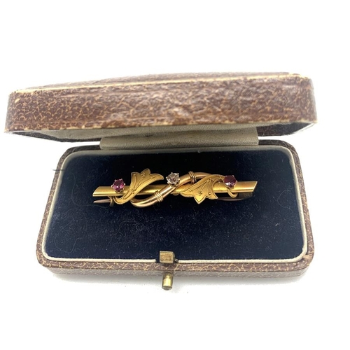 703 - A 15ct gold bar brooch set with central diamond flanked by red stones to each side in original fitte... 