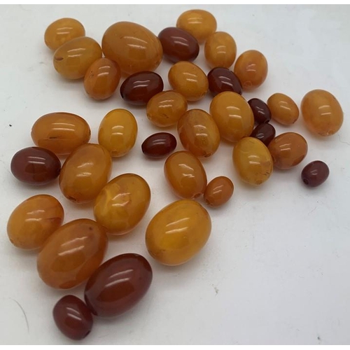 75 - Loose butterscotch and cherry amber beads, largest 2.5cms approx. 51.7gms approx total weight.