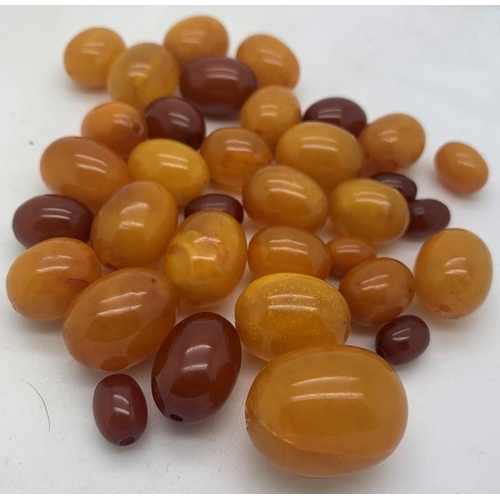 75 - Loose butterscotch and cherry amber beads, largest 2.5cms approx. 51.7gms approx total weight.