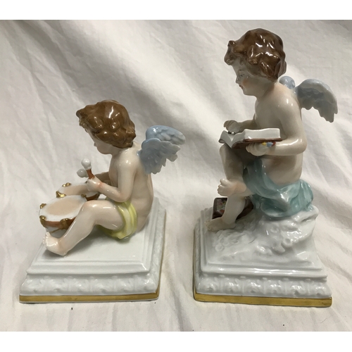 255B - Two Scheibe Albach porcelain figurines. Cherubs, one sat on a plinth painting in a book 15cms h and ... 