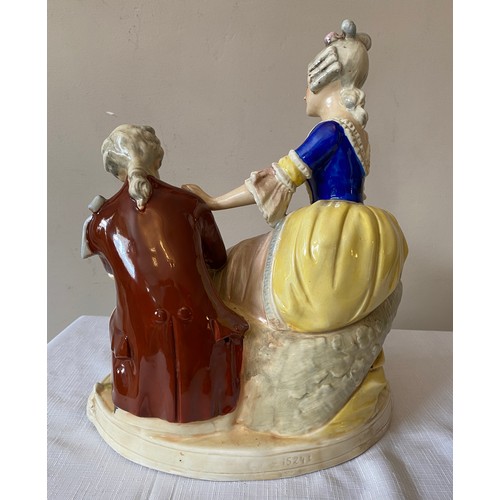 216 - A continental porcelain figurine of a seated lady and a kneeling gentleman. 30cms h x 26cms w at bas... 