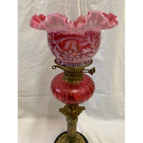 288 - A 19thC cranberry glass oil lamp with cranberry and white glass shade, Corinthian brass column and s... 