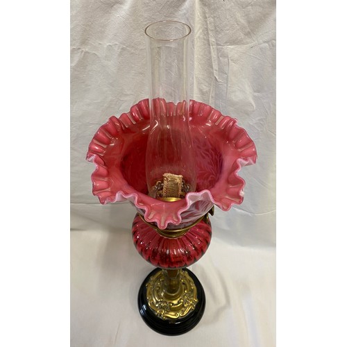 288 - A 19thC cranberry glass oil lamp with cranberry and white glass shade, Corinthian brass column and s... 