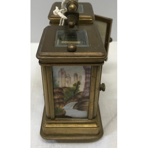 922 - A small brass carriage clock and barometer with carry handle and double key and painted pottery pane... 