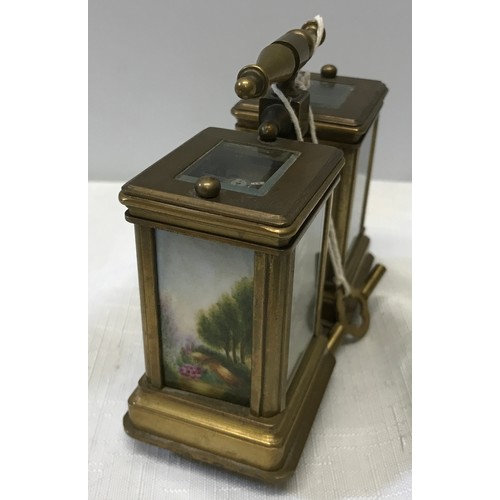 922 - A small brass carriage clock and barometer with carry handle and double key and painted pottery pane... 