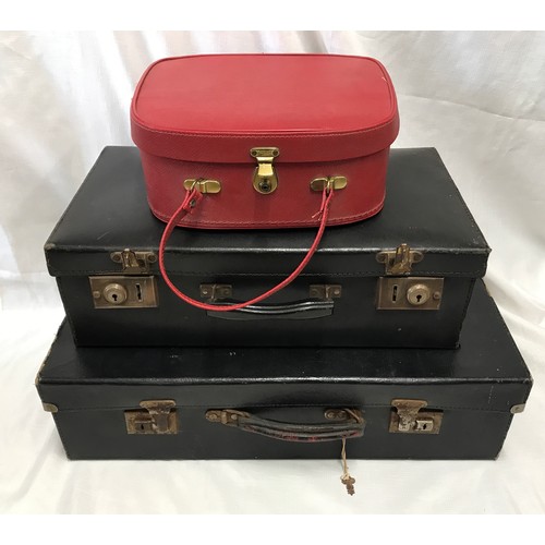 941 - Two black compressed cardboard suitcases 60 x 35cms and 50 x 29cms together with a red vanity case.