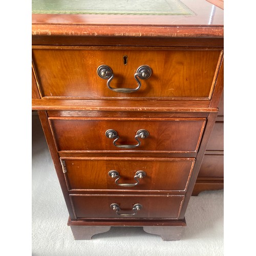 1504 - A 20thC yew wood pedestal desk with green tool leathered top and brass drop handles  and drawers to ... 