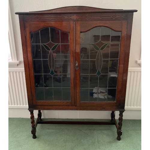 1511 - An oak 2 door display cabinet with leaded clear and coloured glass doors on barley twist legs.