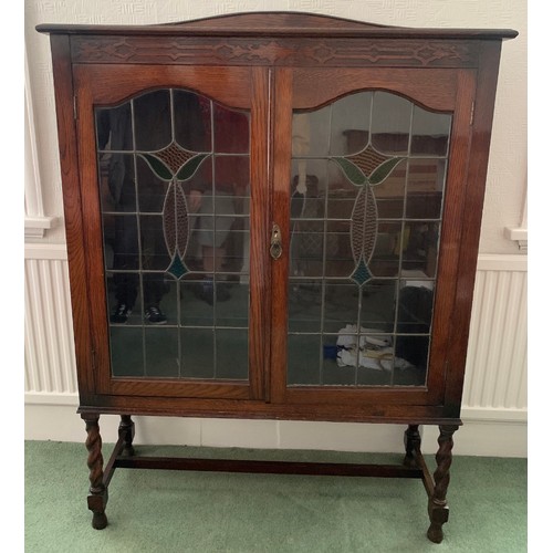 1511 - An oak 2 door display cabinet with leaded clear and coloured glass doors on barley twist legs.