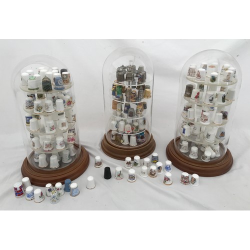 70 - A large collection of thimbles, porcelain white and gilt, metal and enamelled in three dome glass ca... 