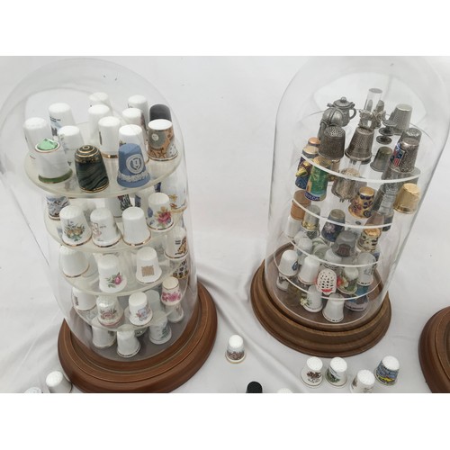 70 - A large collection of thimbles, porcelain white and gilt, metal and enamelled in three dome glass ca... 