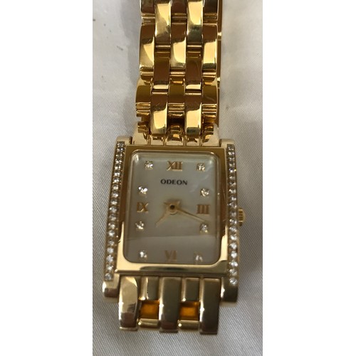 712 - An Odeon ladies wristwatch with a gold plated case and strap. Case set with clear cut stones. Number... 