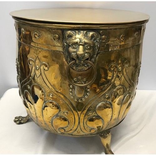 922 - A large brass circular log bucket with embossed decoration, lion head handles, tripod claw feet and ... 