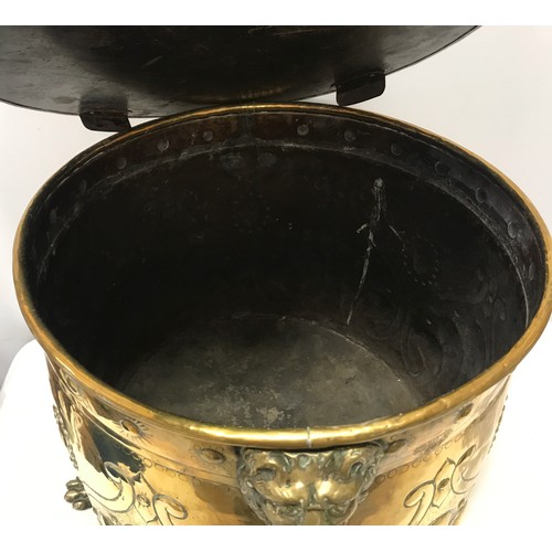 922 - A large brass circular log bucket with embossed decoration, lion head handles, tripod claw feet and ... 