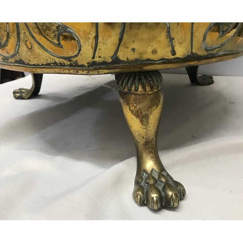 922 - A large brass circular log bucket with embossed decoration, lion head handles, tripod claw feet and ... 