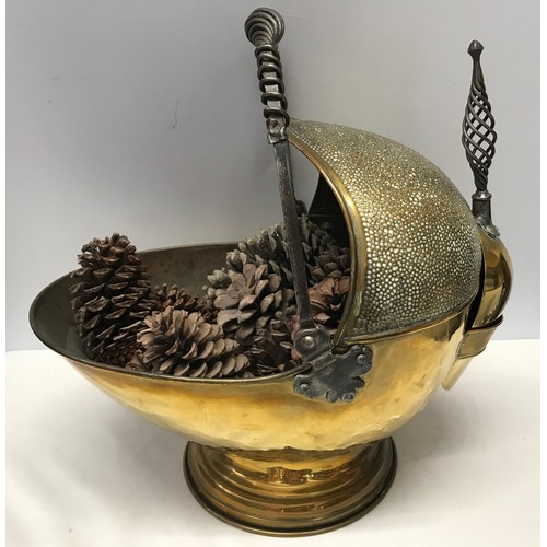 924 - A large brass coal helmet with shovel. Hammered finish with wrought iron handles. Approx. 42cms h x ... 