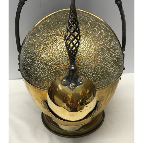 924 - A large brass coal helmet with shovel. Hammered finish with wrought iron handles. Approx. 42cms h x ... 