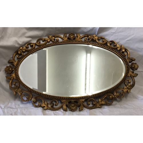 926 - A decorative gilt framed oval bevel edged wall mirror. Frame size 75cms x 47cms.