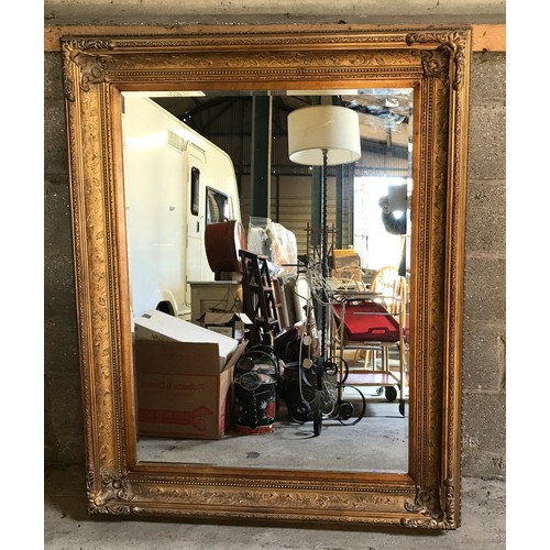 927 - A large gilt framed over mantle mirror with bevel edging. Frame size 122cms x 152cms.