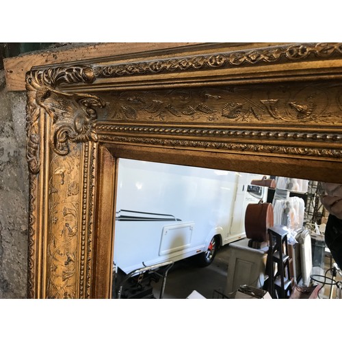 927 - A large gilt framed over mantle mirror with bevel edging. Frame size 122cms x 152cms.