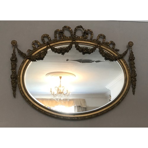 928 - A decorative gilt and gesso framed 19thC oval bevel edged wall mirror. Frame surmounted with bow and... 