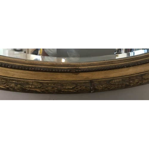 928 - A decorative gilt and gesso framed 19thC oval bevel edged wall mirror. Frame surmounted with bow and... 