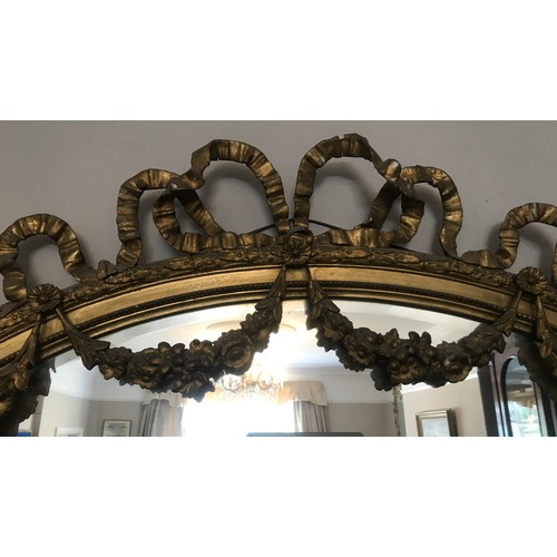 928 - A decorative gilt and gesso framed 19thC oval bevel edged wall mirror. Frame surmounted with bow and... 