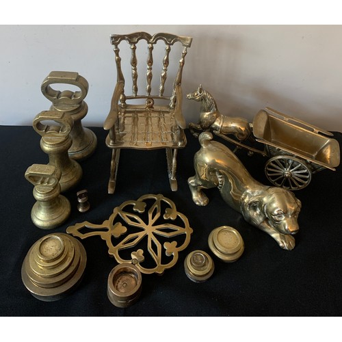 562 - A quantity of brass to include bell and other weights, dog, rocking chair, horse and cart and trivet... 