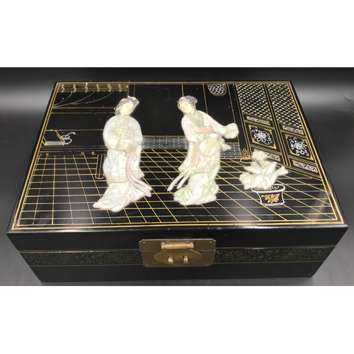 610 - A Japanese black lacquered jewellery box with a mother of pearl lid decorated with Geisha girls and ... 