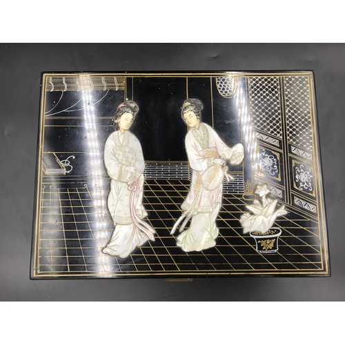 610 - A Japanese black lacquered jewellery box with a mother of pearl lid decorated with Geisha girls and ... 