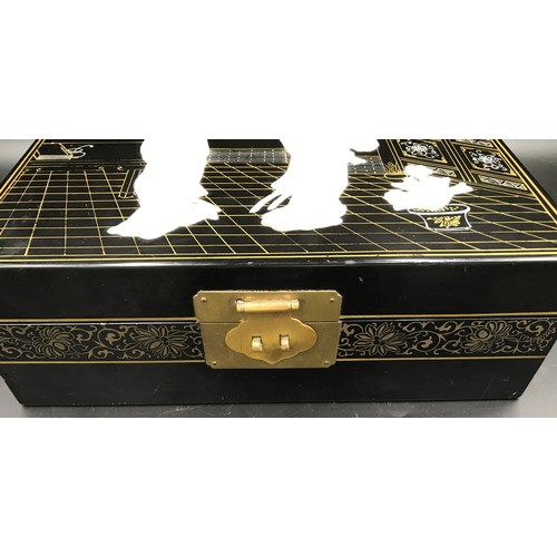 610 - A Japanese black lacquered jewellery box with a mother of pearl lid decorated with Geisha girls and ... 