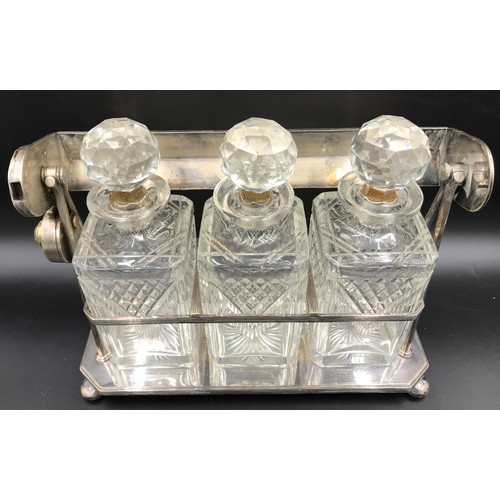 112 - A silver plated framed tantalus containing 3 square decanters with sterling silver stopper bases. 32... 