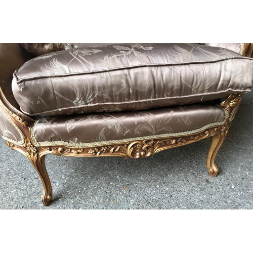 743 - A 19thC carved gilded wooden framed single seat sofa with floral upholstery and a pair of tassel cus... 