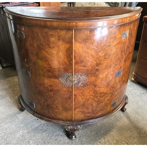 748 - A walnut veneered half round side cabinet with decorative brass fittings, shelved interior and cabri... 