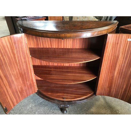 748 - A walnut veneered half round side cabinet with decorative brass fittings, shelved interior and cabri... 