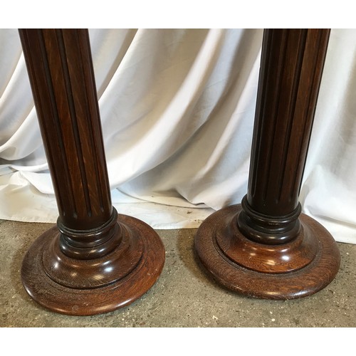 763 - A pair of oak torchere stands with Corinthian columns. 118cms h x 29cms w at base.